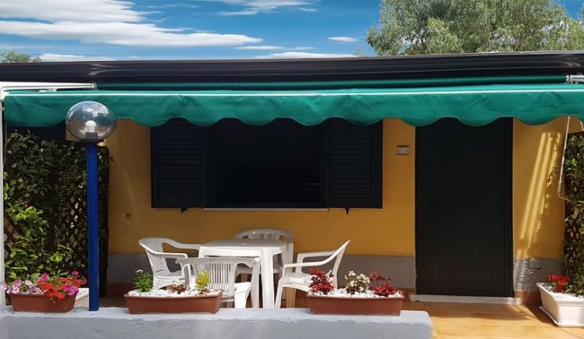 Casa gialla con veranda e tavolo.