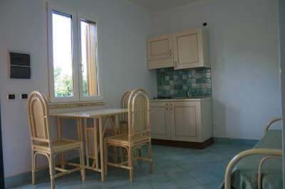 Cucina con tavolo e sedie in legno e mobili beige.