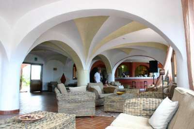 Salone con poltrone in vimini e soffitto ad arco, vista verso il bar.