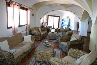 Un salotto spazioso con divani intrecciati, archi e ampie finestre.