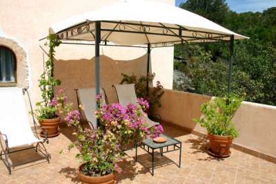 Due sdraio sotto un gazebo con piante fiorite in vaso su una terrazza.