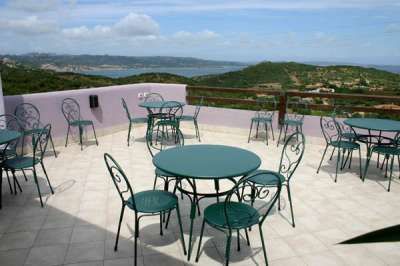 Tavoli e sedie di metallo su una terrazza con vista sul mare.