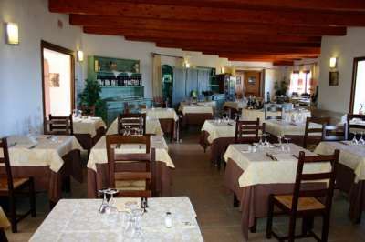 Interno di un ristorante elegante con tavoli apparecchiati e sedie in legno.