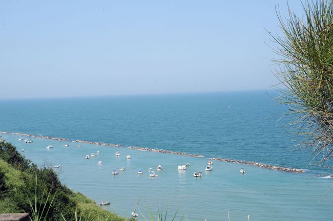 Mare con barche e una barriera rocciosa.