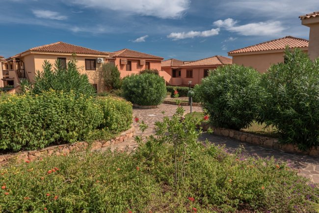 Cortile con edifici rosa e vegetazione lussureggiante.