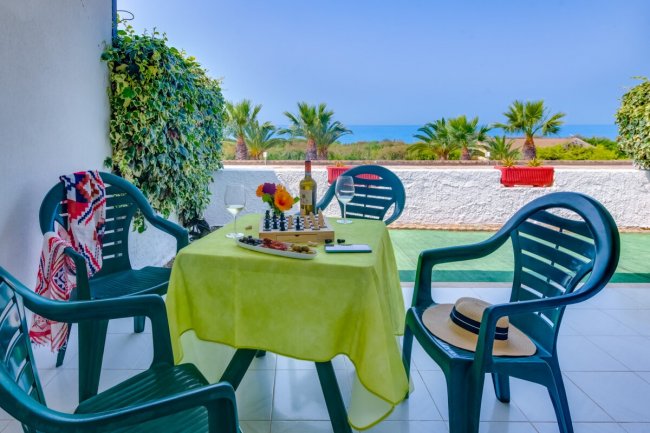 Terrazzino vista mare con tavolo e sedie in plastica.