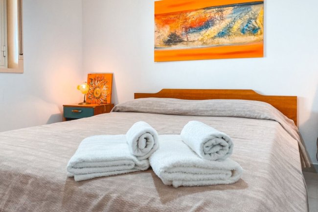 Camera da letto con letto matrimoniale e asciugamani piegati.
