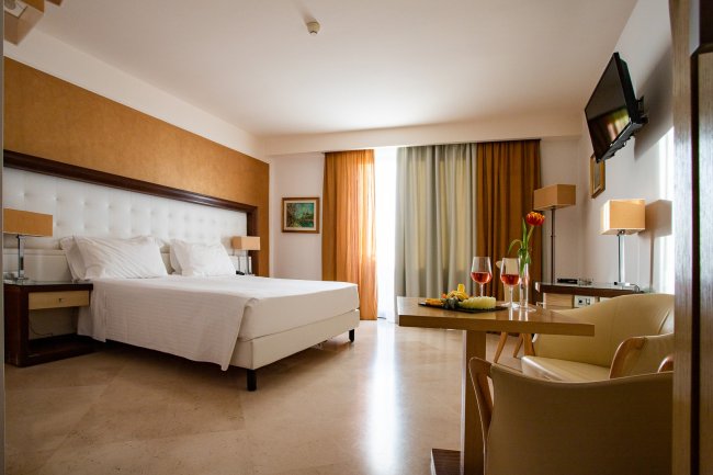 Camera d'albergo con letto matrimoniale e tavolino apparecchiato.