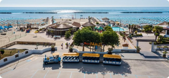 Spiaggia con ombrelloni, trenino e vista sul mare.