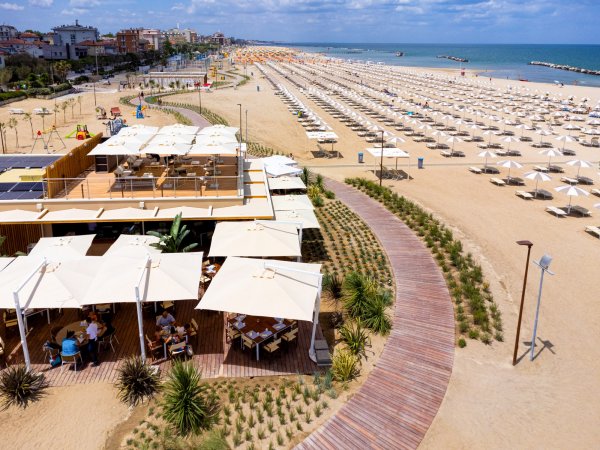 Spiaggia con stabilimento balneare, ombrelloni e sedie a sdraio.