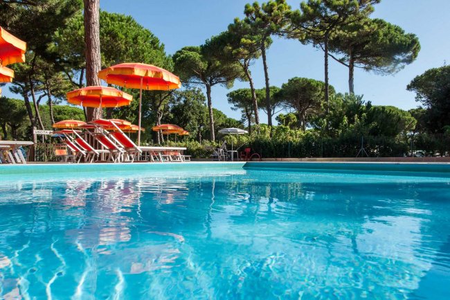 Piscina con ombrelloni arancioni e alberi.
