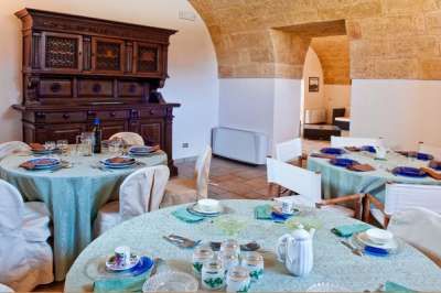 Sala da pranzo con tavoli apparecchiati e mobili in legno intarsiato.