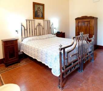 Camera da letto con letto matrimoniale in ferro battuto e mobili antichi.