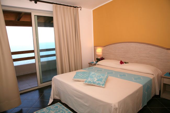 Camera da letto con letto matrimoniale e vista mare.