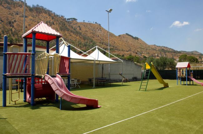Parco giochi all'aperto con scivoli colorati e montagna sullo sfondo.