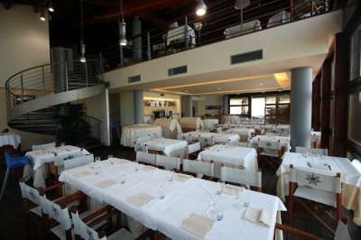 Sala da pranzo elegante con tavoli apparecchiati e una scala a chiocciola sullo sfondo.