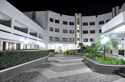 Cortile notturno di un edificio moderno con pavimento a zig-zag e piante verdi.