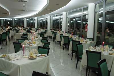 Sala da pranzo elegante con tavoli quadrati apparecchiati e luci soffuse.