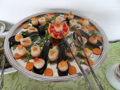 Vassoio con cozze ripiene su letto di rucola e carote, al centro decorazione vegetale.