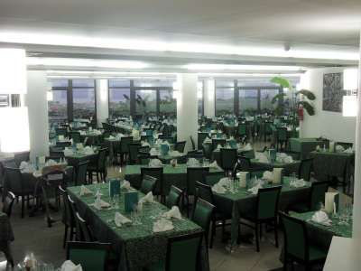 Sala da pranzo ampia con tavoli apparecchiati e sedie verdi.