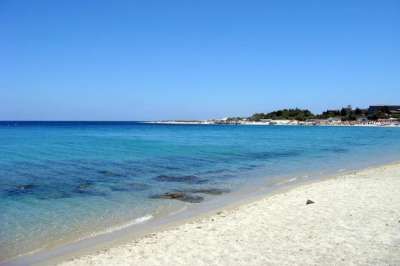 Una spiaggia sabbiosa con mare turchese e cielo sereno.