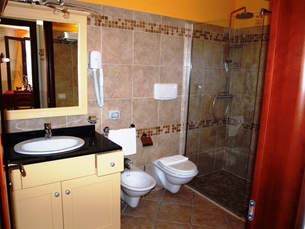 Bagno con lavandino nero, bidet, wc e doccia con piastrelle beige.