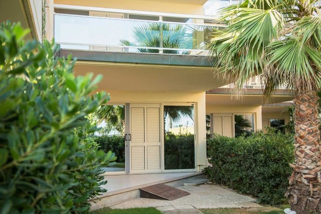 Ingresso di una casa con giardino e palme.
