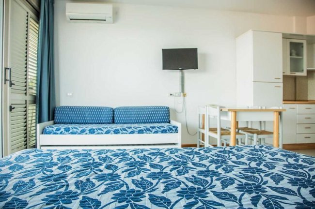 Letto e divano blu in stanza luminosa.