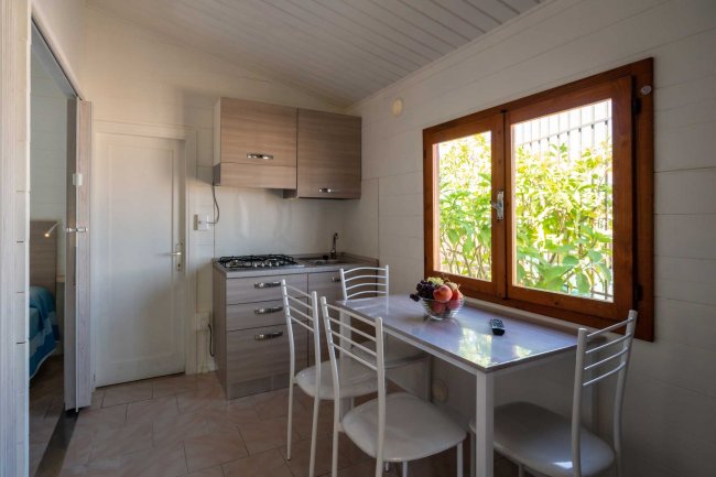 Cucina compatta con tavolo bianco e sedie.