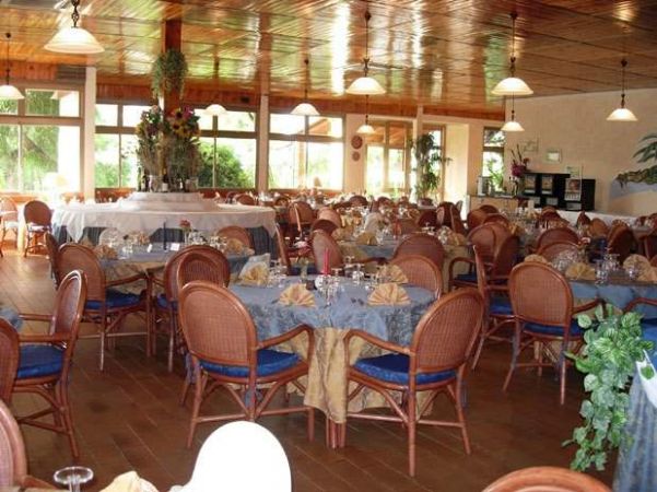 Sala ristorante elegante con tavoli apparecchiati e sedie in vimini.