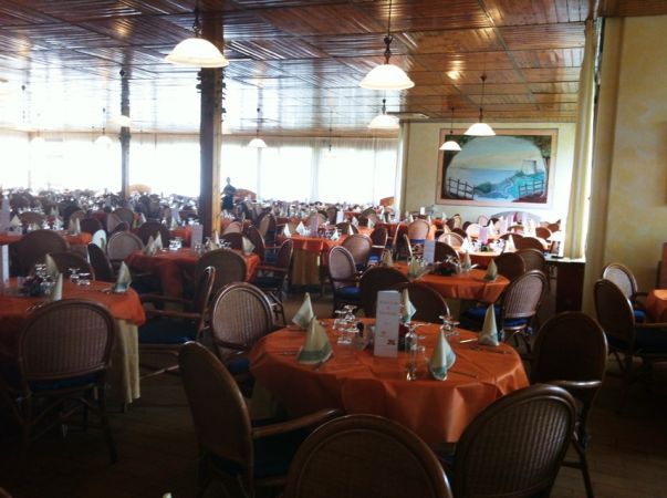 Ristorante ampio con tavoli apparecchiati e sedie in vimini.