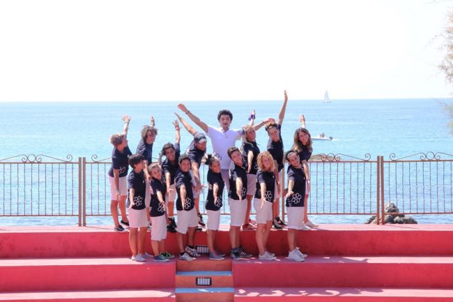 Gruppo di persone su gradini davanti al mare.