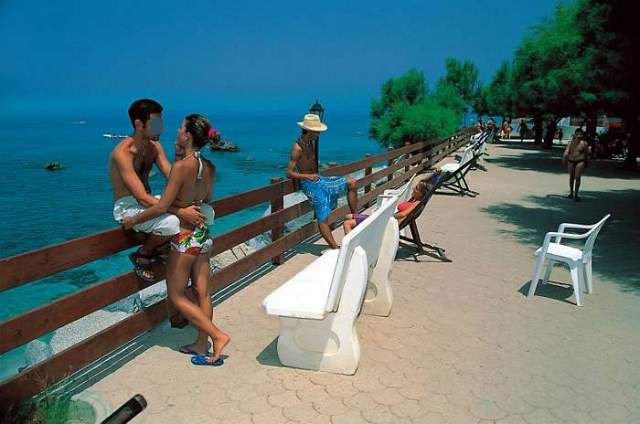 Coppia si abbraccia vicino a una ringhiera, vista mare.