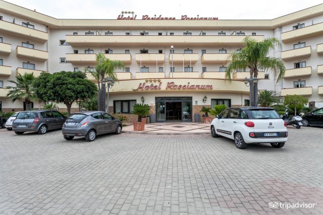 Facciata di un hotel con auto parcheggiate.