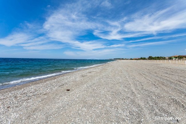 Spiaggia di ciottoli sotto un cielo blu.
