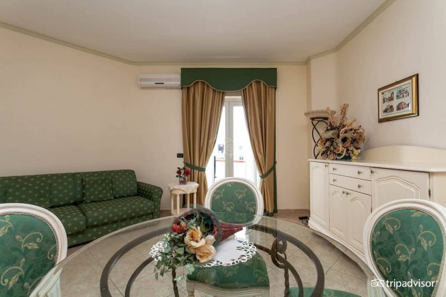 Soggiorno con divano verde e tavolo rotondo.