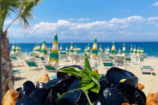 Vista mare da spiaggia con piatto di cozze.