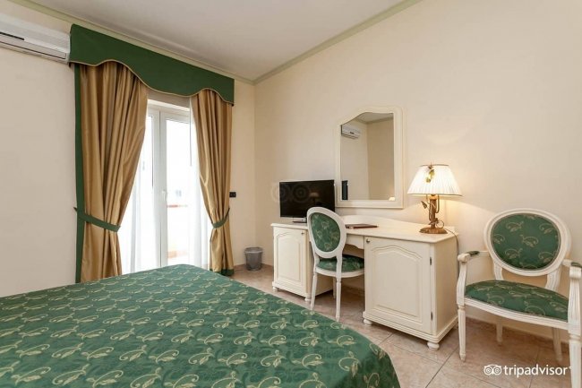 Camera con scrivania, sedia e letto matrimoniale.