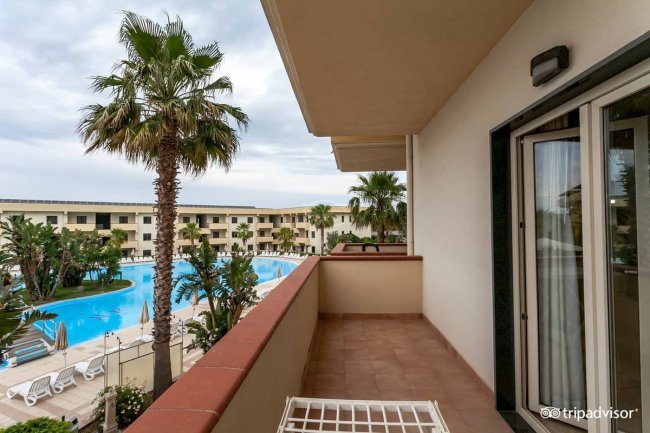 Balcone con vista piscina e palme.