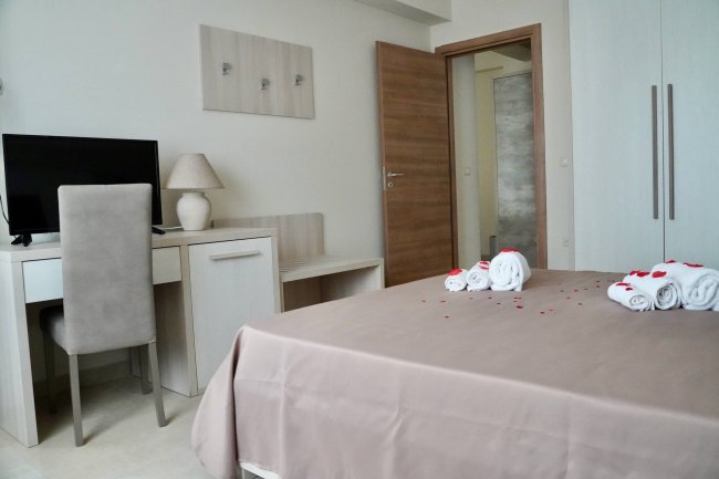 Camera con letto coperto, scrivania, sedia e TV.