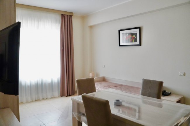 Camera con tavolo, sedie, letto singolo e finestra.