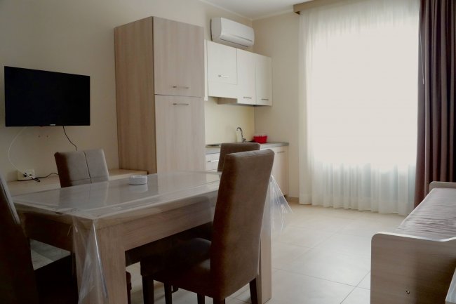 Sala da pranzo con tavolo, sedie e angolo cottura.