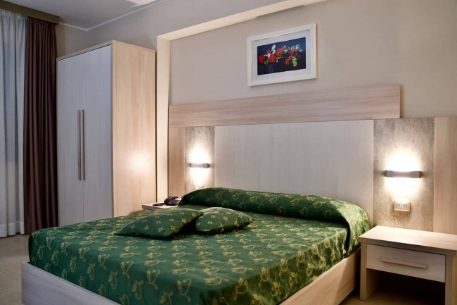 Camera con letto matrimoniale verde e armadio chiaro.