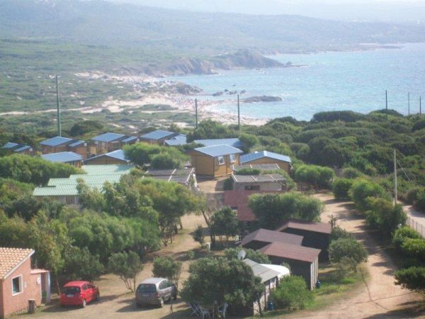 Vista aerea di un campeggio con bungalow e vegetazione vicino al mare.