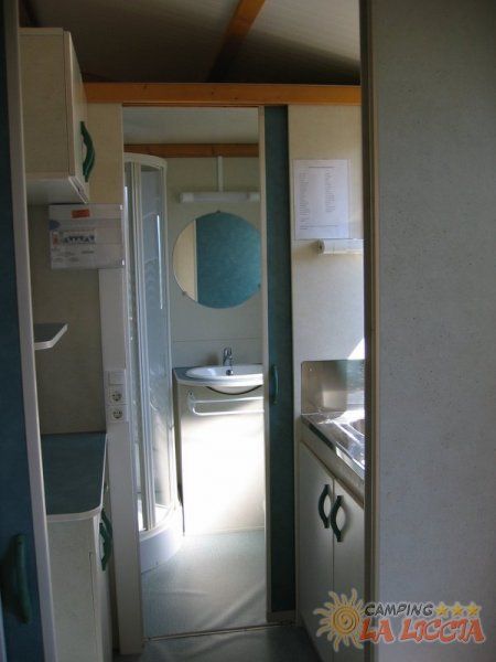 Interno di un bagno con doccia e lavandino, visibile attraverso una porta aperta.