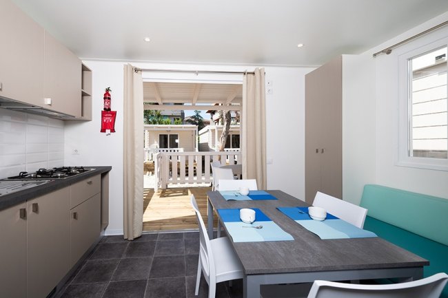 Sala da pranzo con tavolo e sedie, vista su veranda.