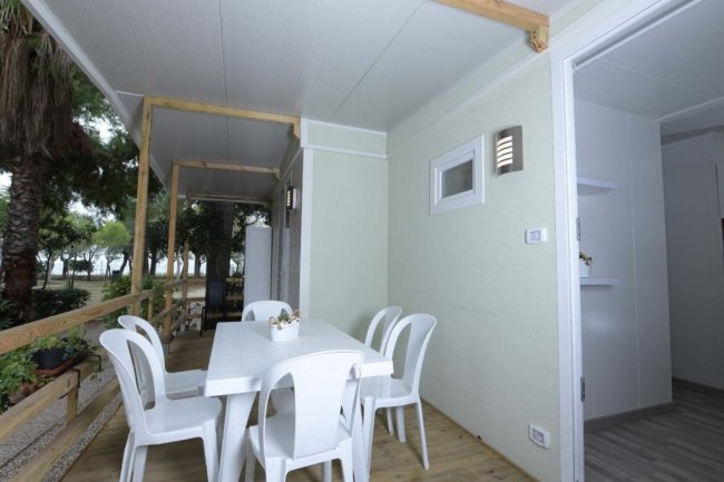 Veranda con tavolo bianco e sedie in plastica.