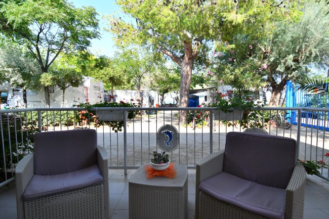 Due poltrone con cuscini viola su una veranda ombreggiata.