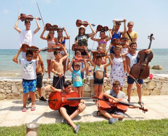 Gruppo di persone con strumenti musicali al mare.