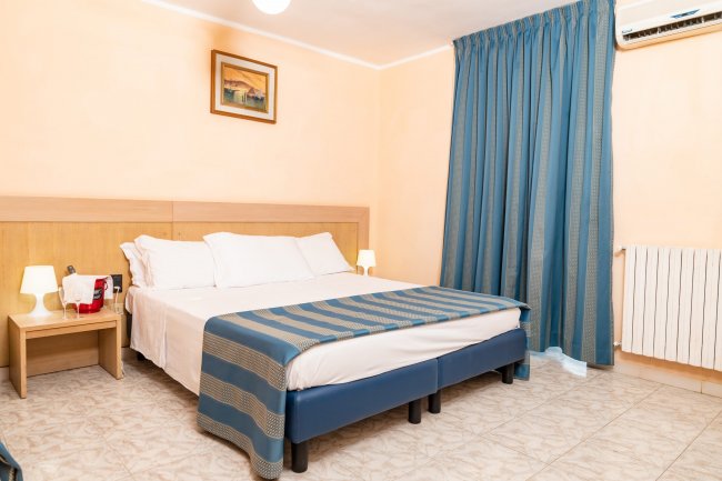 Camera d'hotel con letto matrimoniale e tende blu.